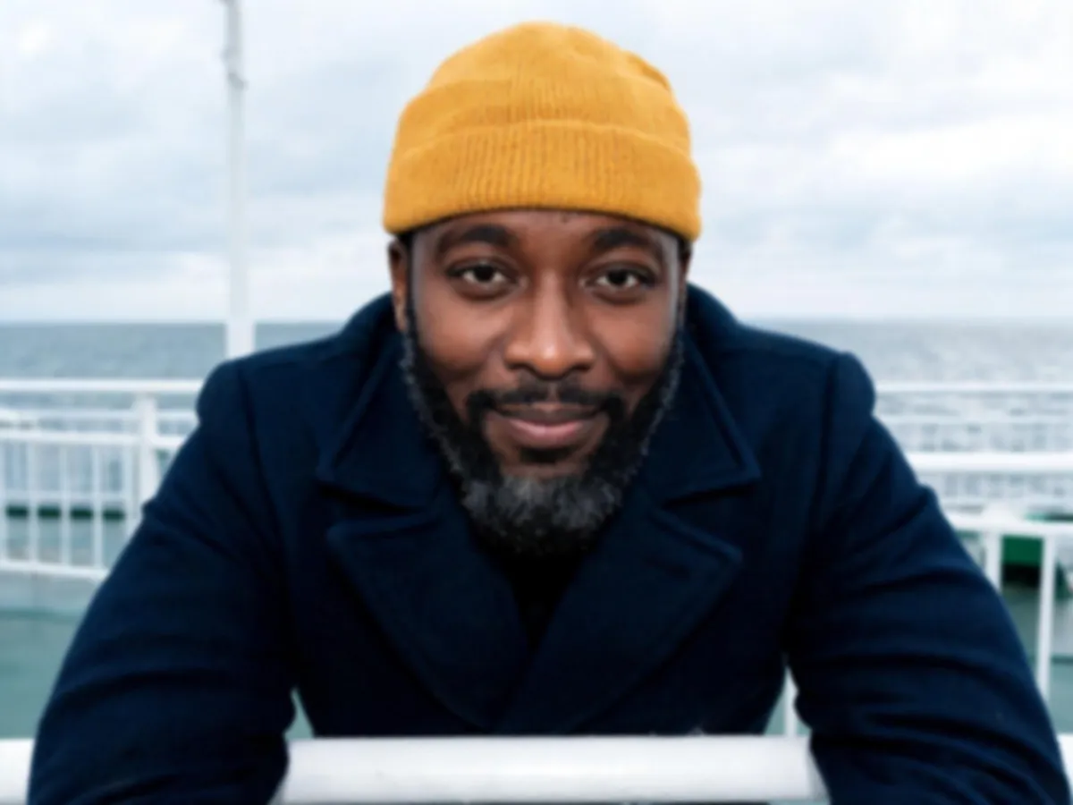 Soft portrait of a man in a mustard beanie on a ferry deck — the original before unblurring